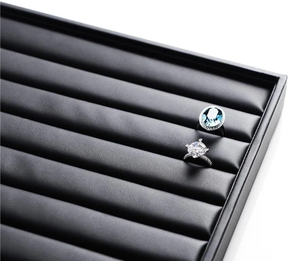 Black ring display tray with soft velvet slots showcasing two elegant rings.