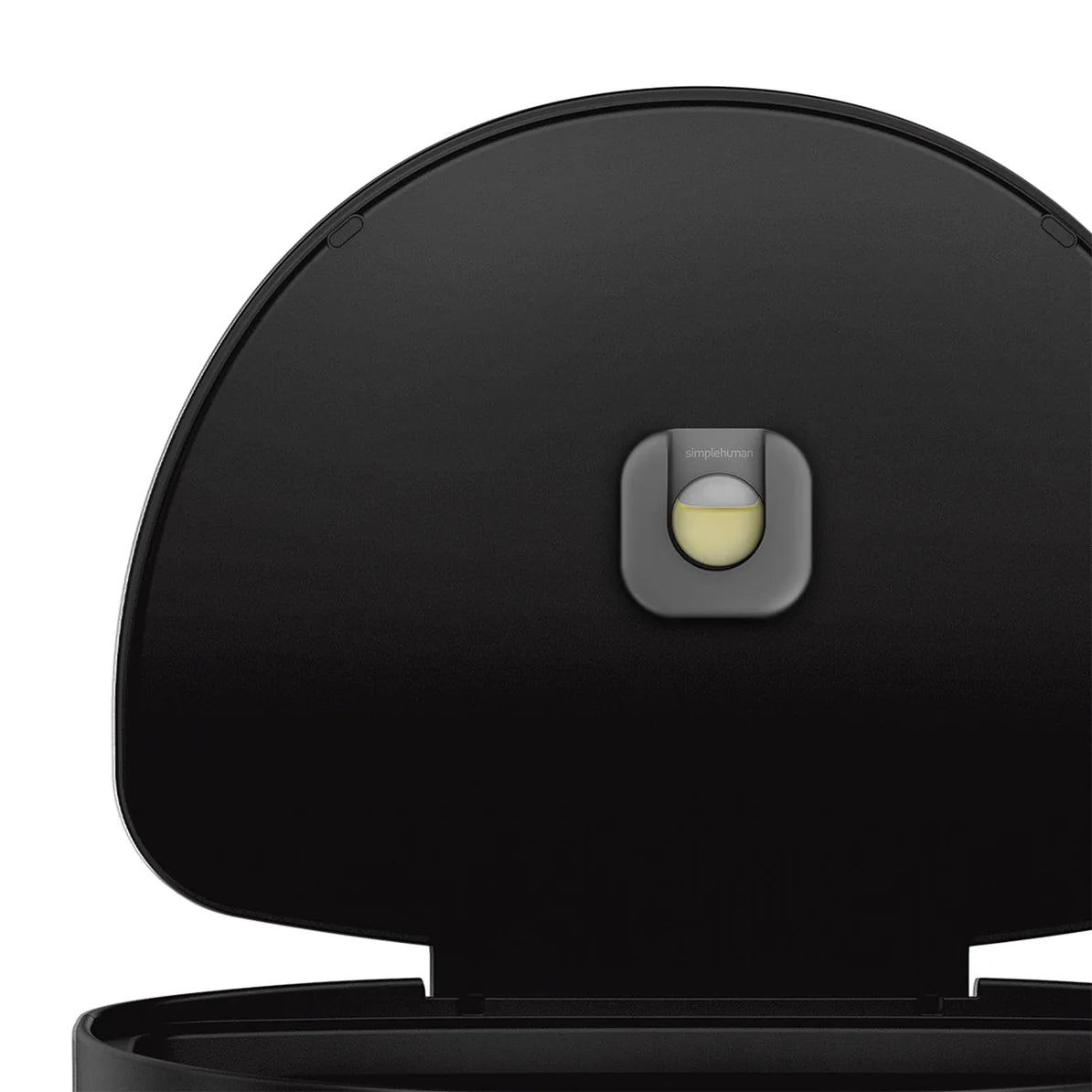 The image displays the interior lid of a Simplehuman black cylindrical trash can. The lid is open, revealing the Simplehuman brand logo and a circular mechanism that is likely part of the motion-activated sensor system. The design is sleek and modern, consistent with Simplehuman's aesthetic, and the black color adds to the sophisticated appearance of the product. The sensor mechanism is centrally located, ensuring that the lid opens efficiently when motion is detected.