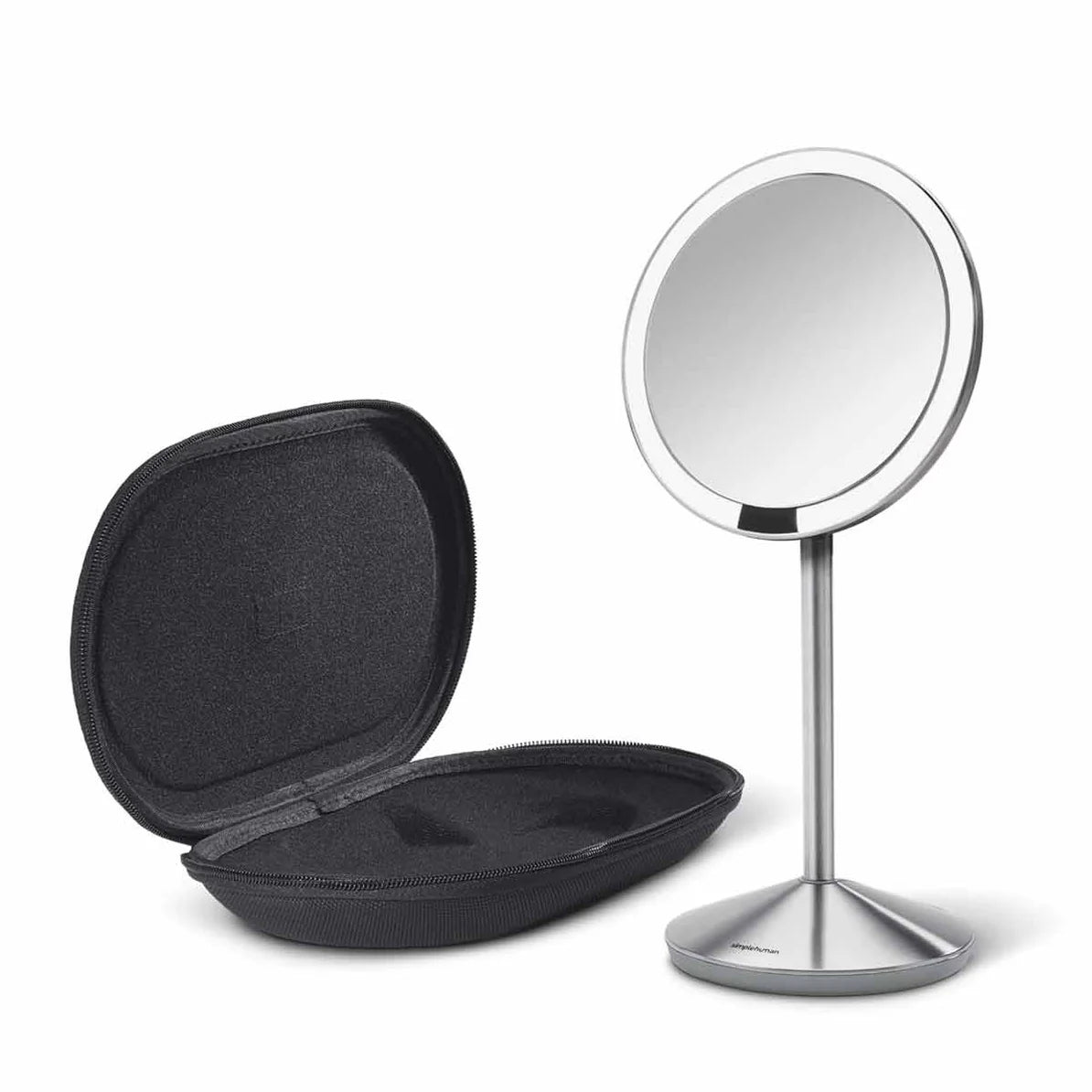  A sleek, circular vanity mirror with a brushed stainless steel stand is displayed alongside an open, black, hard-shell case. The mirror features a thin bezel and is mounted on a slim, conical stand, providing a modern and minimalist appearance. The hard-shell case has a soft interior, designed to securely hold the mirror when not in use, offering both protection and portability. The overall design is stylish and functional, suitable for travel or home use in a contemporary setting.