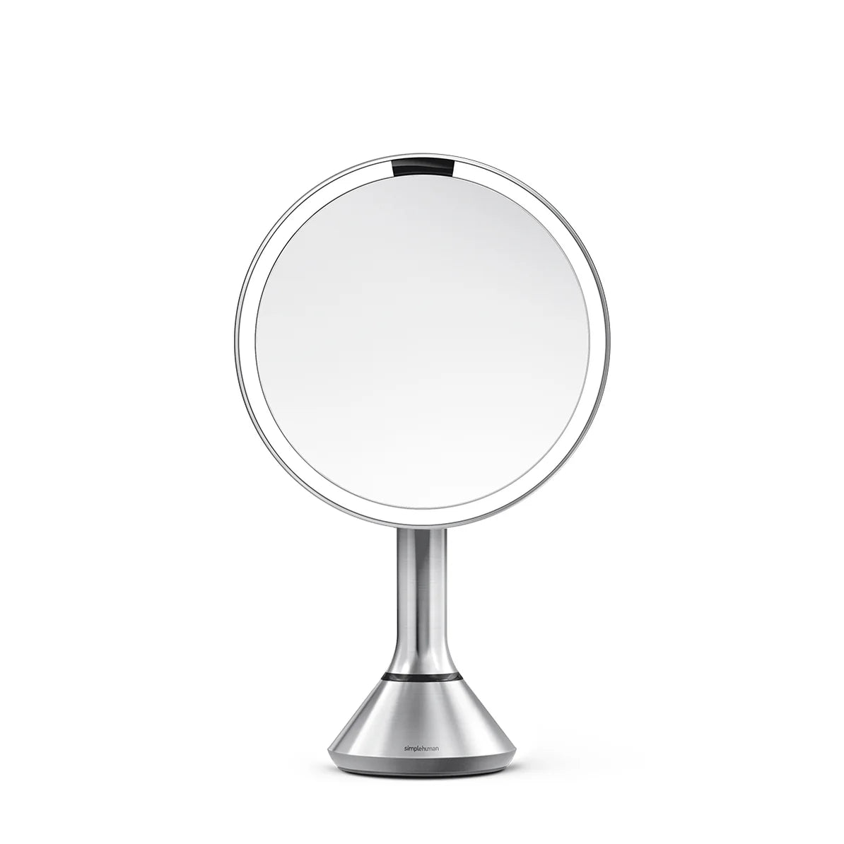 This image displays a Simplehuman makeup mirror with a sleek, stainless steel finish. The mirror features a clean, modern design with a round, well-lit surface surrounded by an LED light ring, which provides bright and even illumination, ideal for makeup application or detailed grooming tasks.  The mirror is mounted on a streamlined stand that tapers into a sturdy base, ensuring stability on any surface. The stainless steel finish gives it a polished, high-end appearance, making it a stylish addition to any