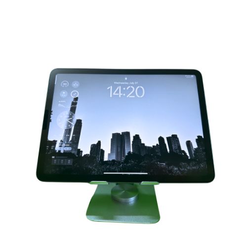 A front view of a tablet mounted on a white 360 rotating stand. The stand provides a secure hold and allows for flexible positioning and rotation. The tablet's screen displays a cityscape with a clock showing the time as 14:20. The stand has a sturdy base and an adjustable arm.