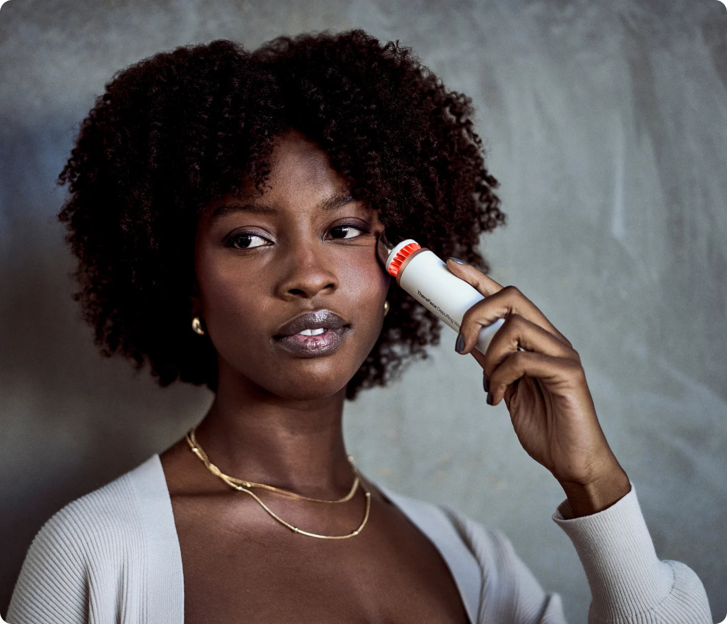 Woman using the white TheraFace Depuffing Wand with the heat-treatment LED glowing