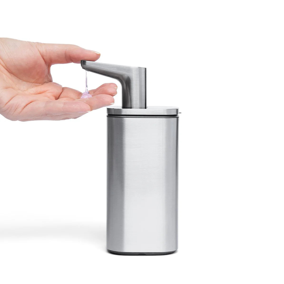 The image shows a hand positioned under the nozzle of a sleek, silver automatic soap dispenser, which is dispensing soap. The dispenser has a modern design with a brushed metallic finish and a slightly angled nozzle for easy soap dispensing. The design is minimalistic and elegant, typical of Simplehuman products, making it suitable for contemporary home or commercial environments. The product effectively combines functionality with a high-end aesthetic.